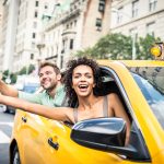 Interracial couple driving on a taxi in Manhattan - Tourists sightseeing New York on a yellow cab